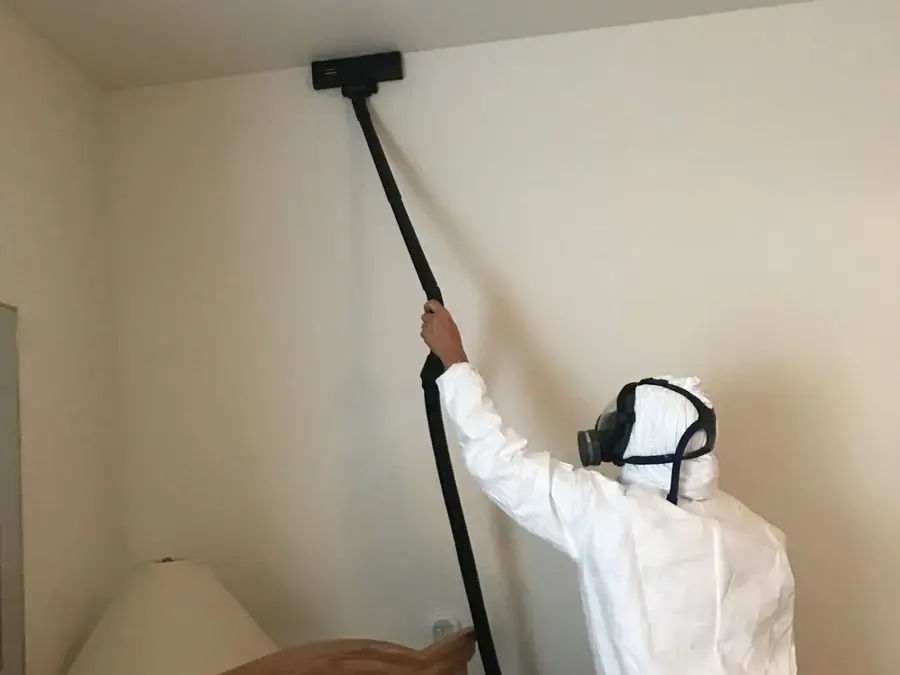 Technician in a protective suit applying antimicrobial to a wall during a Largo water loss