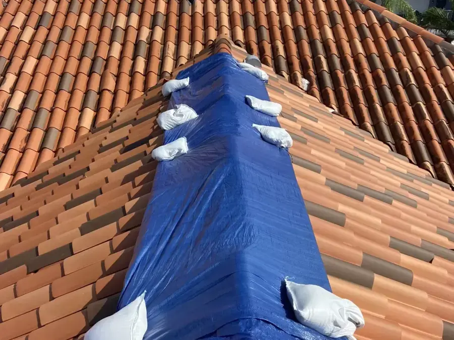 Tarp secured over a barrel tile roof ridge after storm damage