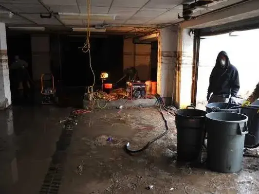 Crew clearing floodwater and debris from a flooded ground floor after a storm