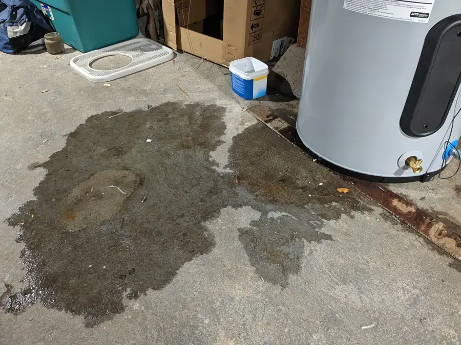 Water spreading across a garage floor from a leaking water heater tank